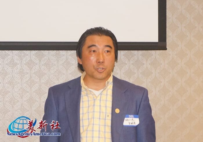 A man in a blue suit standing next to a white wall.