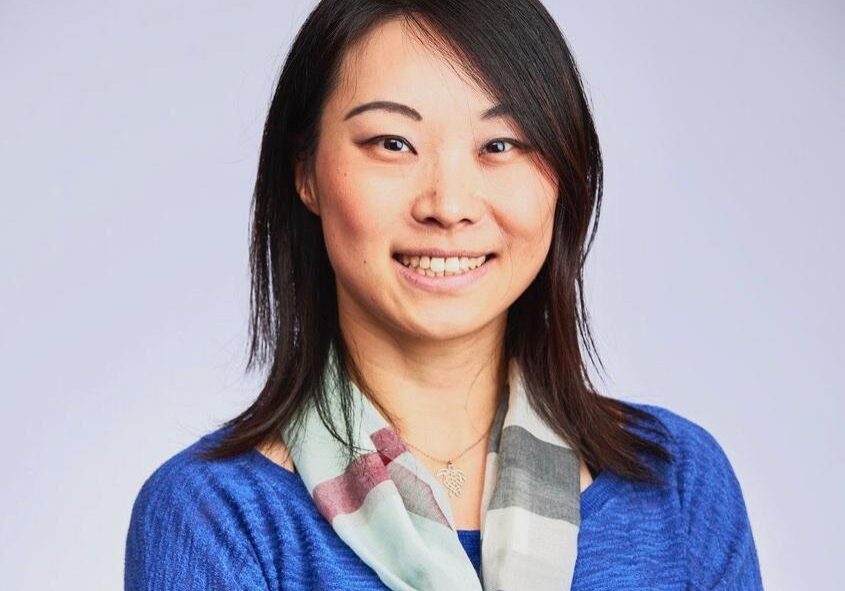 A woman with long hair wearing a blue shirt and a scarf.