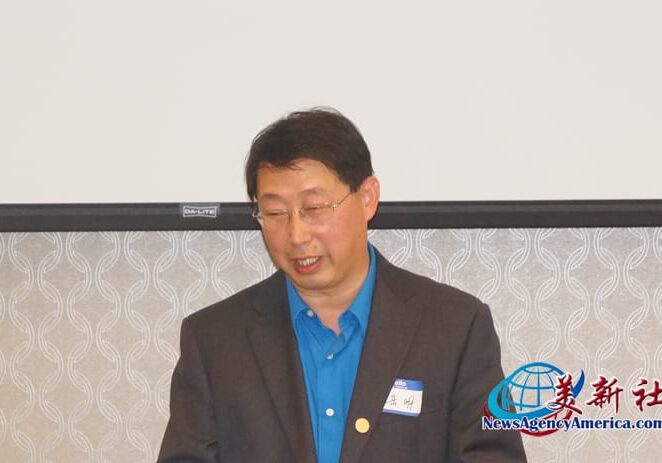 A man in a suit and tie standing next to a projector screen.